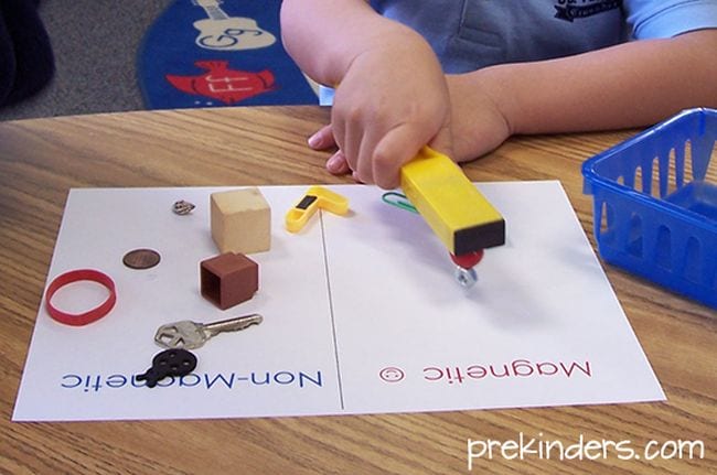 Preschool science student using a bar magnet to test other objects